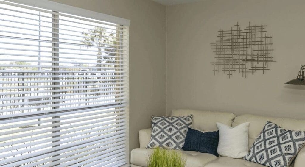 Comfortable modern living room with white sofa and large window showing outdoor view, located at City Base Vista in San Antonio, Texas.